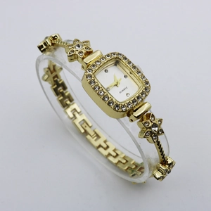 Detail view of gold square bracelet watch with rhinestone flower band and white dial