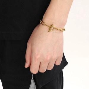 Dettaglio di un bracciale dorato in acciaio inossidabile con chiusura a T sul polso di una modella