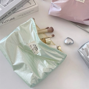 Macro shot of mint green pearlescent makeup bag with metal zipper and woven label detail