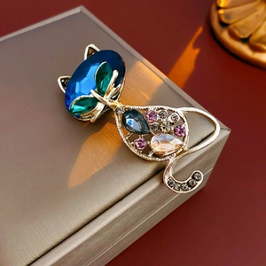 Close-up of a golden cat brooch with colorful rhinestones and blue gemstone accent