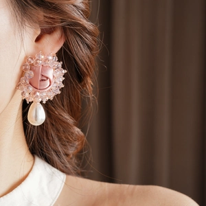 Detail of pink silk rose earring with teardrop pearl and beads on female model