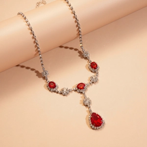 Gros plan d'un collier vintage argenté avec pendentif goutte rubis et pierres en cristal