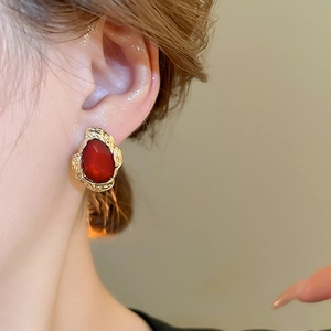 Macro shot of vintage style earrings with deep red gemstones and gold textured frames