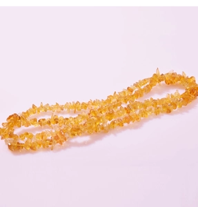 Macro detail of irregular yellow crystal chips strung into a natural polished necklace