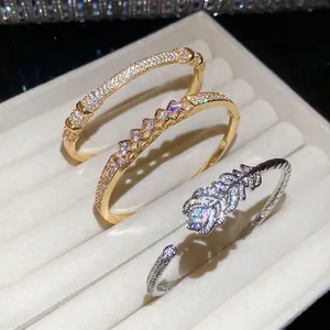 Gold and silver plated zircon bangles with feather and crown motifs in velvet box