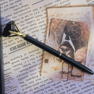 Gros plan d'un stylo à pierre de cristal noire sertie d'or sur un fond de journal vintage