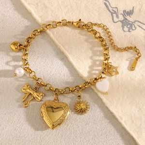 Detailed close-up of 18K gold plated charm bracelet with heart locket and butterfly pendants