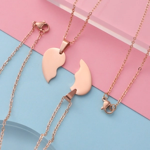 Detail of rose gold split heart pendants on geometric pink and blue background