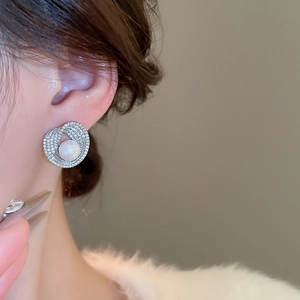 Close-up of spiral zircon hoop earrings with pearls worn on a model's ear