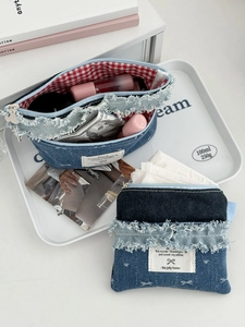 Detail of denim makeup bag set with distressed edges and red gingham lining texture