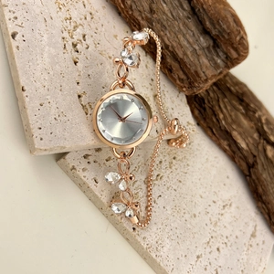 Detail of rose gold bracelet watch featuring leaf-shaped crystals and a silver dial