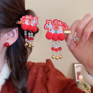 Detail of red festive hair clips with embroidery, pom-poms, and golden bells