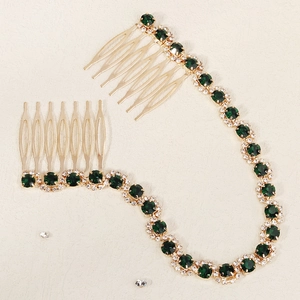 Detailed view of bridal hair comb with green crystals and gold chain on beige background