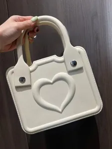 Detailed view of white EVA handbag with embossed heart pattern and silver metal buckles
