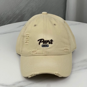 Detail of vintage beige baseball cap featuring distressed holes and Paris embroidery