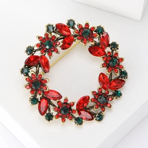 Macro detail of a rhinestone wreath brooch with red and green crystals on gold base