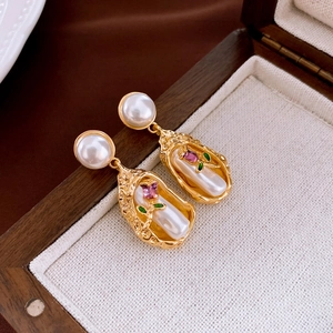 Close-up of vintage flower earrings with pearls and enamel in a wooden jewelry box