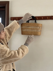 Detalle de guantes de punto a rayas grises táctiles con un bolso de mano tejido