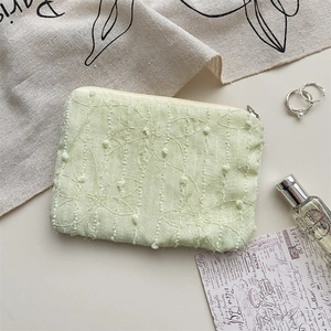 Macro view of mint green fabric coin pouch featuring 3D floral embroidery and metal zipper
