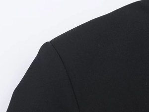 Dettaglio cucitura spalla su tutina nera a doppio petto con taglio stile blazer