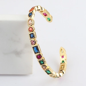 Adjustable golden bracelet with colorful geometric zircons on white marble