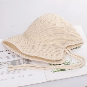 Detail of beige woven fisherman hat featuring textured knit design and long chin straps