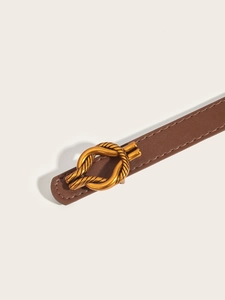 Close-up of a slim brown leather belt featuring a gold knotted metal buckle on white