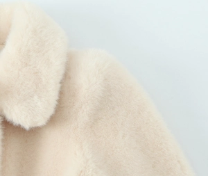 Detailed close-up of soft cream faux fur collar and plush texture on winter jacket