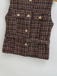 Detailed macro shot of textured tweed fabric with ornate gold embossed metal buttons