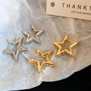 Close-up of gold and silver hollow star-shaped hoop earrings on white textured paper