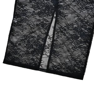 Close-up of intricate floral lace fabric and slit detail on a black bodycon dress