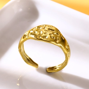 Macro shot of gold-plated stainless steel ring with hammered texture on white tray