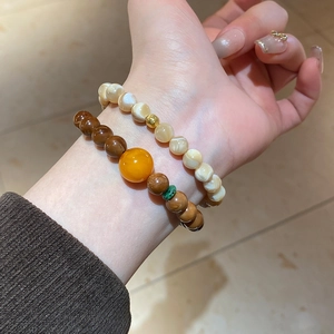 Detail view of double-layered beaded bracelet with shell pearls and amber-like resin beads