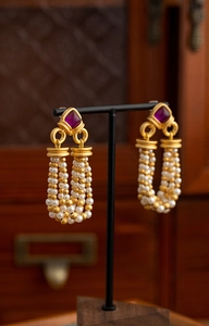 Detail of vintage palace style earrings with purple gemstones and pearl tassels