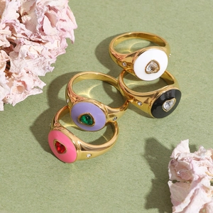 Golden heart-shaped rings set with colorful enamel and inlaid gemstones on a green background