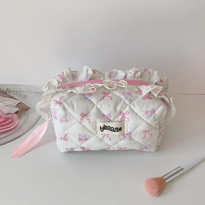 Close-up of quilted floral makeup bag with pink bow pattern and elegant lace trim detail
