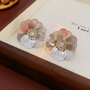 Macro shot of silver hollow wire floral studs with central sparkling rhinestones