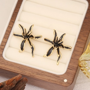 3D black floral stud earrings with gold plating displayed in a wooden jewelry box