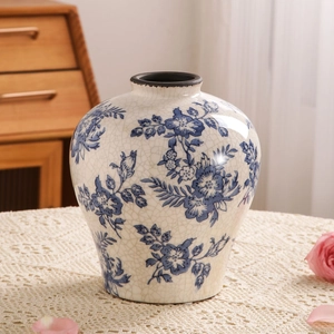 Vaso di ceramica blu e bianca con smalto craquelé su tovaglia di pizzo elegante