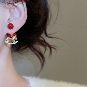 Detailed close-up of 18K gold plated rocking horse earrings with red beads and zircon