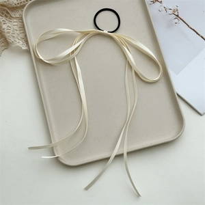Detail of cream white bow ribbon with black elastic hair tie on a decorative tray