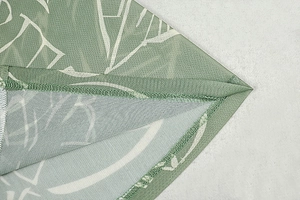 Macro view of light green mesh fabric with white leaf print and fine stitching details