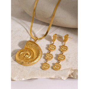 Detailed view of 18k gold plated flat snake chain necklace and shell earrings on stone