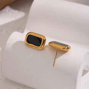 Detail of minimalist gold square stud earrings with black rectangle inlay on display