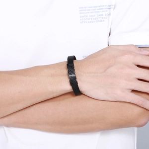 Gros plan d'un bracelet noir en silicone avec boucle ajourée en acier inoxydable ondulé