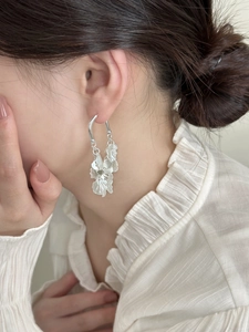 Detailed close-up of silver geometric petal tassel earrings worn on a female model
