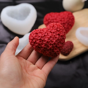 Nahaufnahme der roten Herzkerze mit Blumenrelief neben weißer Silikonform