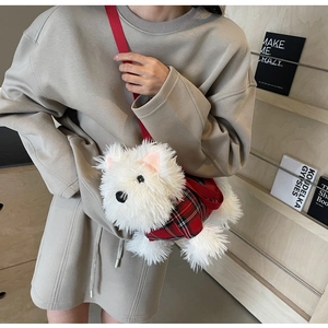 Close-up of Westie plush bag in red plaid vest against a warm wooden bookshelf background
