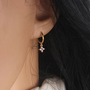 Elegant gold hoop earrings with purple clover zirconia pendant on model's ear