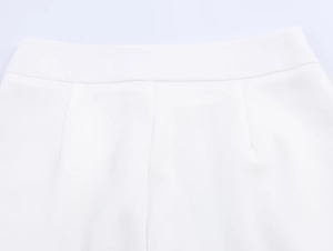 Close-up detail of high-waist white linen trousers showing fine stitching and fabric texture